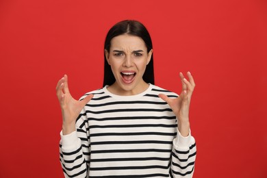 Angry young woman on red background. Hate concept