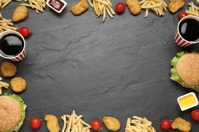 Frame of delicious fast food menu on black table, flat lay. Space for text