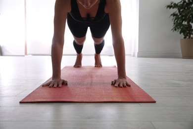 Photo of Woman practicing plank asana in yoga studio, closeup. Phalankasana pose