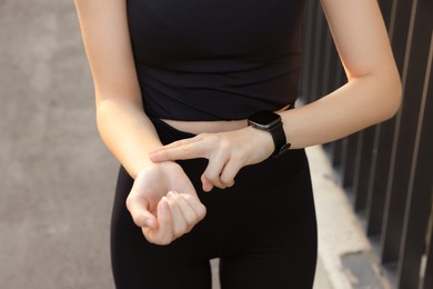 Woman checking pulse after training outdoors, closeup