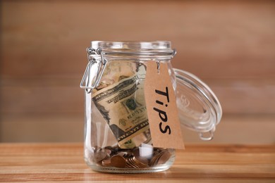 Glass jar with tips on wooden table, closeup