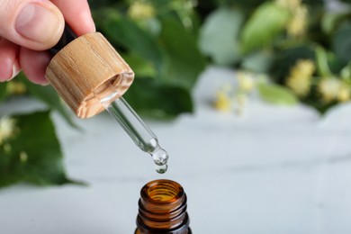 Woman pouring essential oil from pipette into bottle, closeup. Space for text