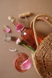 Photo of Flat lay composition with rose wine, wicker bag and beautiful pink peonies on brown background
