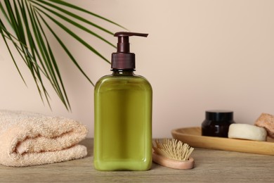 Bottle of shampoo on wooden table near beige wall