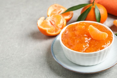 Photo of Delicious tangerine jam on light grey table. Space for text