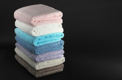 Different fresh soft terry towels on dark background. Space for text