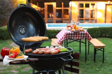 Barbecue grill with sausages and vegetables outdoors