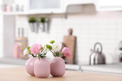 Vases with beautiful flowers on table in kitchen interior. Space for text