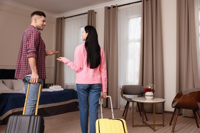 Happy couple with suitcases walking into hotel room