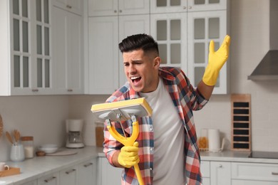 Man with mop singing while cleaning at home