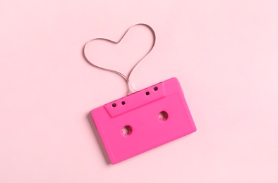 Music cassette and heart made with tape on pink background, top view. Listening love song