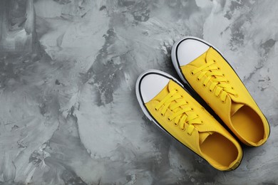 Pair of yellow sneakers on grey stone table, flat lay. Space for text