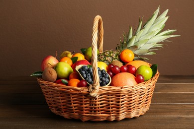 Assortment of fresh exotic fruits in wicker basket on wooden table