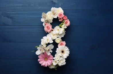 Number 8 made of beautiful flowers on blue wooden table, flat lay. International Women's day