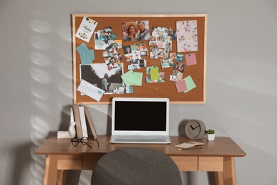 Stylish workplace with vision board and laptop