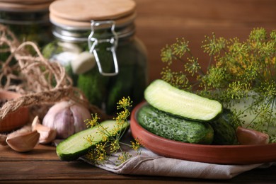 Photo of Fresh cucumbers and other ingredients prepared for canning on wooden table