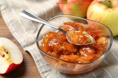 Tasty apple jam in glass bowl and fresh fruits on table, closeup