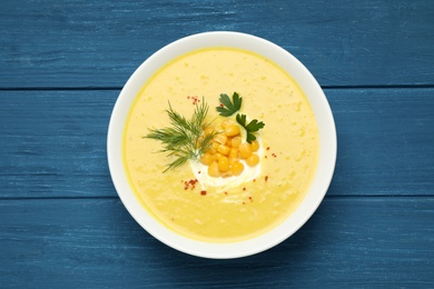 Delicious creamy corn soup served on blue wooden table, top view