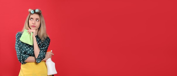 Photo of Young housewife with detergent and rag on red background. Space for text