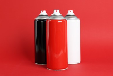 Colorful cans of spray paints on red background