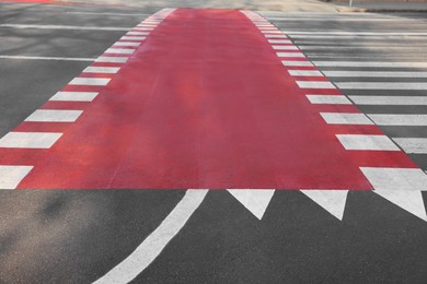 Part of bicycle lane painted red along pedestrian crossing on road