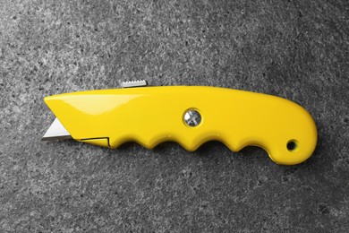 Yellow utility knife on grey table, top view. Construction tool