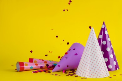 Colorful party hats and other festive items on yellow background. Space for text