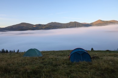 Picturesque mountain landscape with camping tents in foggy morning