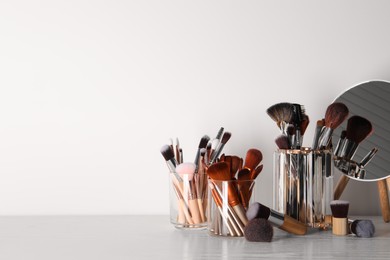 Photo of Set of professional brushes and mirror on wooden table against white background, space for text