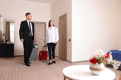 Happy businesspeople with suitcases walking into hotel room