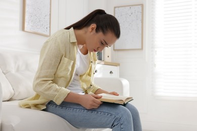 Young woman with poor posture reading book at home