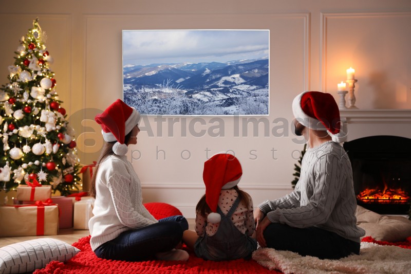 Image of Family watching TV in room decorated for Christmas