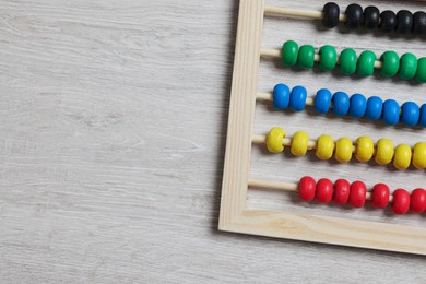 Photo of Funny math game. Colorful toy abacus on white wooden table, top view. Space for text