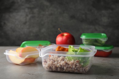 Set of plastic containers with fresh food on light grey table