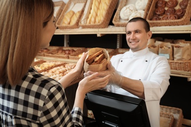 Woman buying tasty pastry in bakery shop