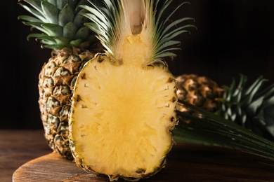 Photo of Whole and cut pineapples on wooden board, closeup