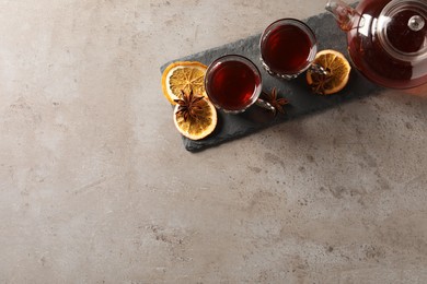 Photo of Slate plate with glasses of traditional Turkish tea in vintage holders, pot, dried orange and anise on light grey table, top view. Space for text