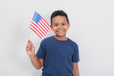 Happy African-American boy holding national flag on light background