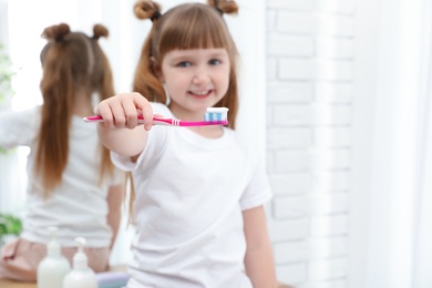 Little girl brushing teeth in bathroom at home. Space for text