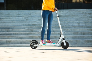 Woman riding electric kick scooter outdoors on sunny day