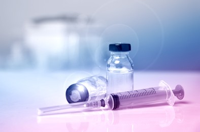 Syringe and vials on table against blurred background