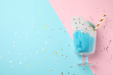 Glass with cotton candy and macaroon on color background, top view. Space for text