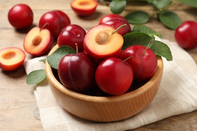 Delicious ripe cherry plums with leaves on wooden table