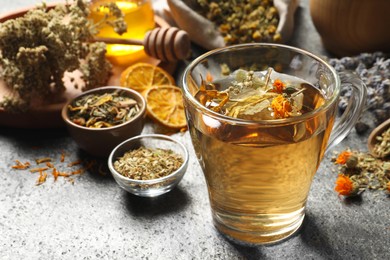Freshly brewed tea and dried herbs on grey table, closeup