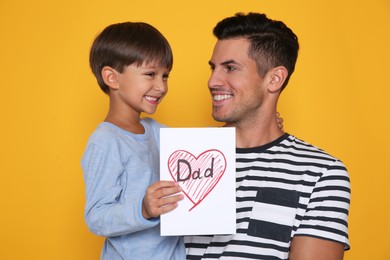 Little boy greeting his dad with Father's Day on yellow background