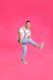 Happy attractive man dancing on pink background