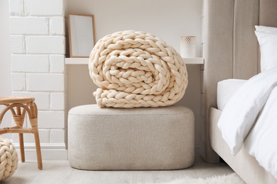 Soft chunky knit blanket on ottoman in stylish room interior
