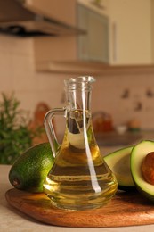 Photo of Fresh avocados and jug of cooking oil on beige marble table in kitchen