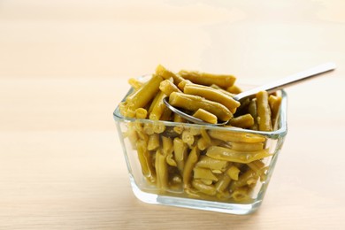 Canned green beans in bowl on wooden table
