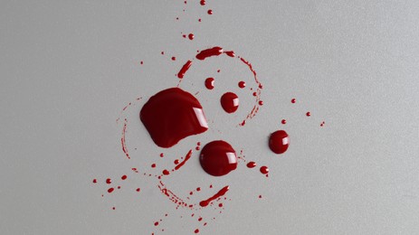 Stain and splashes of blood on grey background, top view